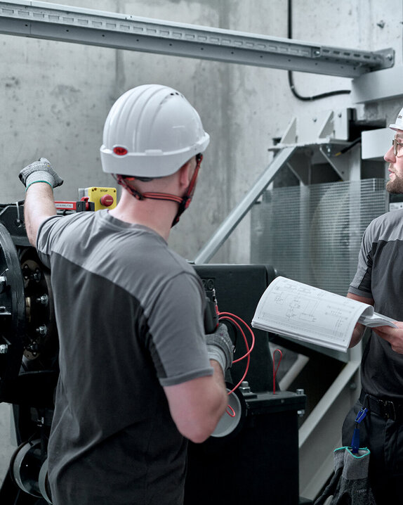 Haushahn Antrieb - zwei Techniker arbeiten an Aufzugsanlage