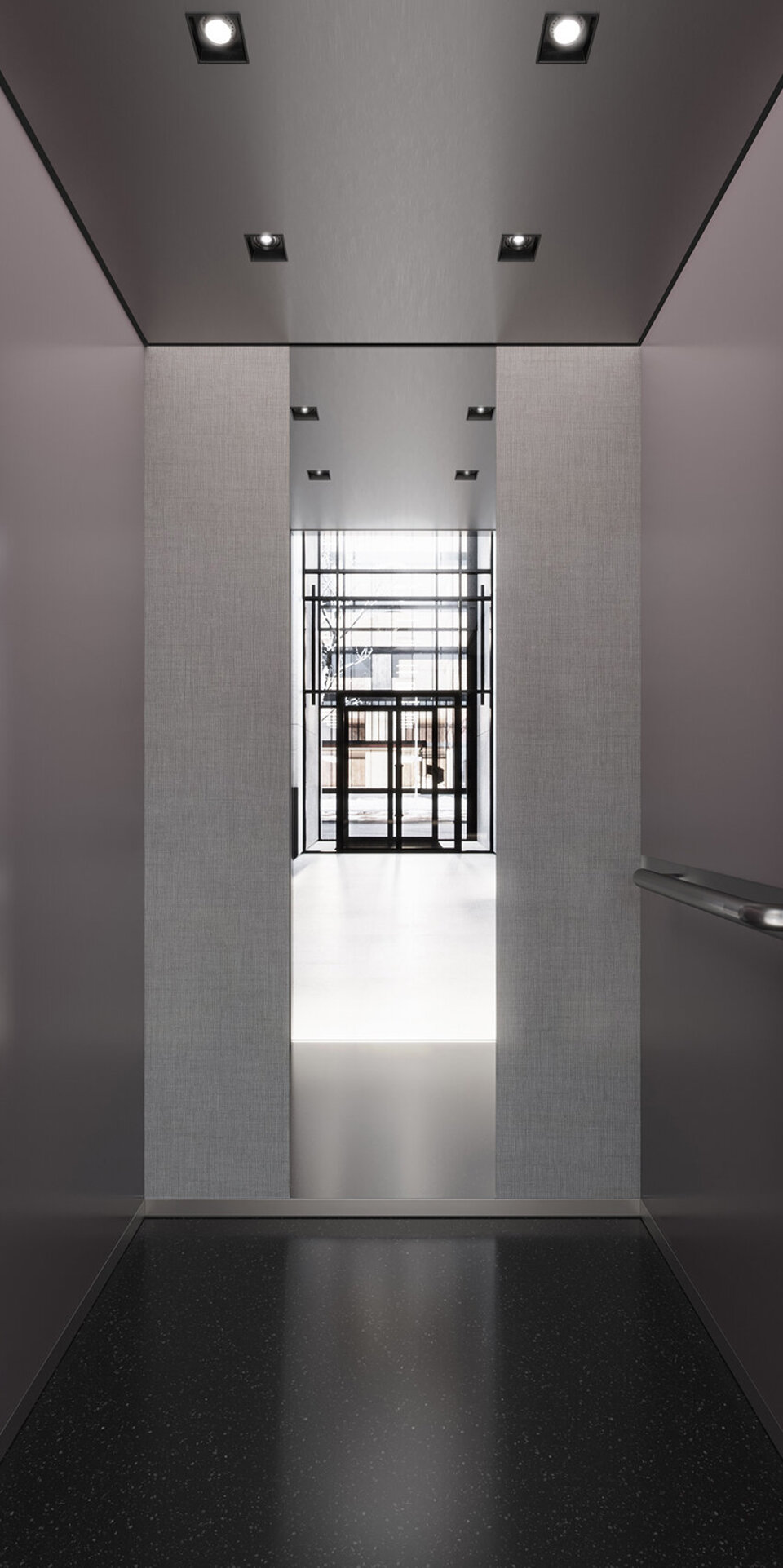 Modernes Aufzugsinnere mit eleganten dunklen Wänden, einem halbhohen Spiegel auf der Rückseite und Deckenleuchten, silberner Verkleidung und einer digitalen Etagenanzeige mit der Nummer 2. 