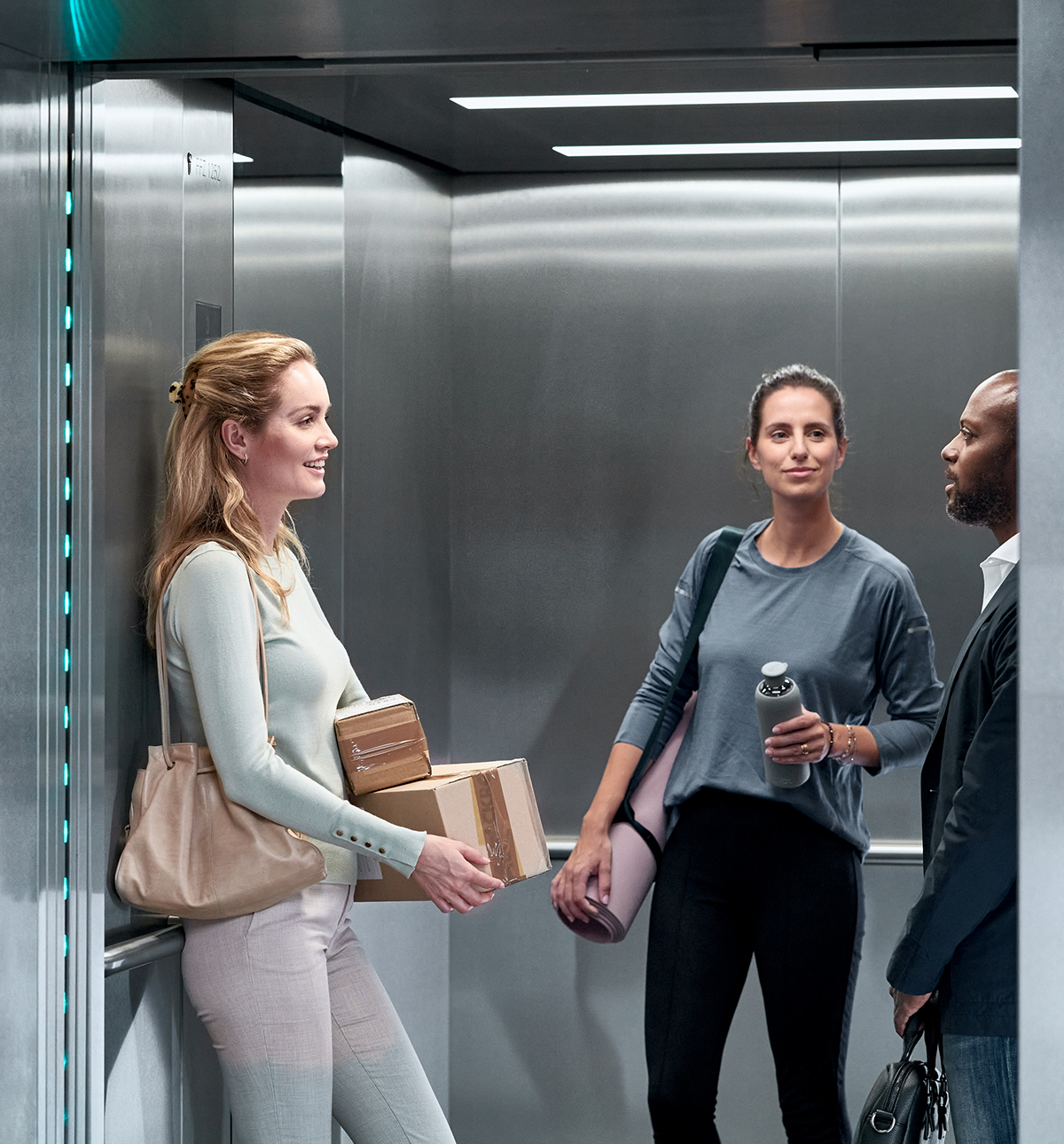 Haushahn Menschen - drei Personen im Aufzug in Gesprächssituation